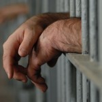 bigstock_Hands_Behind_Bars_4796934